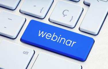 A computer keyboard with a bright blue key that features the word ‘webinar’ -